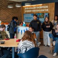 Large group of students inside new success center, laughing and talking with each other